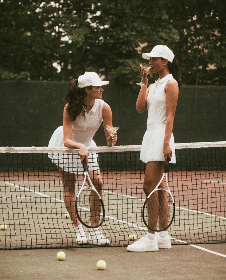 Two members on a tennis court in club whites